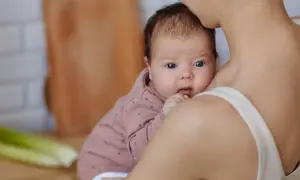 Mama tuli karmić piersią, zastanawia się czego nie jeść przy karmieniu piersią. Na stole seler i zielenina.