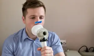 Mężczyzna wykonuje spirometrię, badanie co wykrywa choroby płuc.