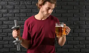 Mężczyzna z hantlem zastanawia się, czy piwo bezalkoholowe ma alkohol.