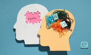 Dwie głowy symbolizujące chorobę dwubiegunową: jedna z napisem "Bipolar" na różowym tle, druga z plątaniną kolorowych nitek i emotikonami smutnej i uśmiechniętej buźki.