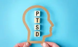 Klocki z literami P, T, S, D układają się w napis PTSD wewnątrz sylwetki głowy. Test na zespół stresu pourazowego.