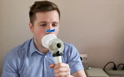 Mężczyzna wykonuje spirometrię, badanie co wykrywa choroby płuc.