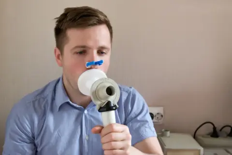 Mężczyzna wykonuje spirometrię, badanie co wykrywa choroby płuc.