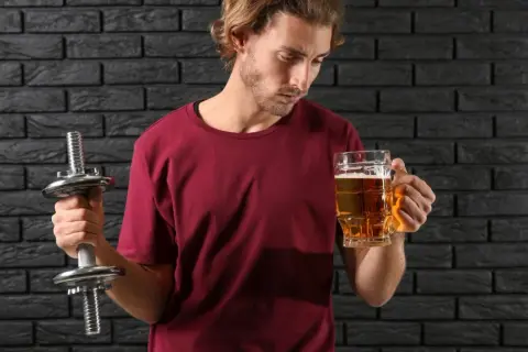 Mężczyzna z hantlem zastanawia się, czy piwo bezalkoholowe ma alkohol.