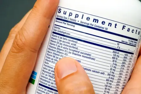Palec wskazuje na etykietę "Supplement Facts", wyjaśniając, co to jest suplement diety i jakie składniki zawiera.