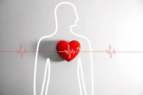 Czerwone serce z linią EKG symbolizuje kołatanie serca w nocy. Sylwetka człowieka podkreśla problem zdrowotny.
