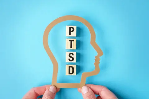 Klocki z literami P, T, S, D układają się w napis PTSD wewnątrz sylwetki głowy. Test na zespół stresu pourazowego.