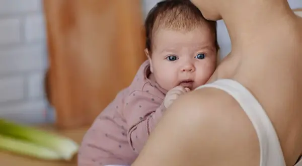 Mama tuli karmić piersią, zastanawia się czego nie jeść przy karmieniu piersią. Na stole seler i zielenina.