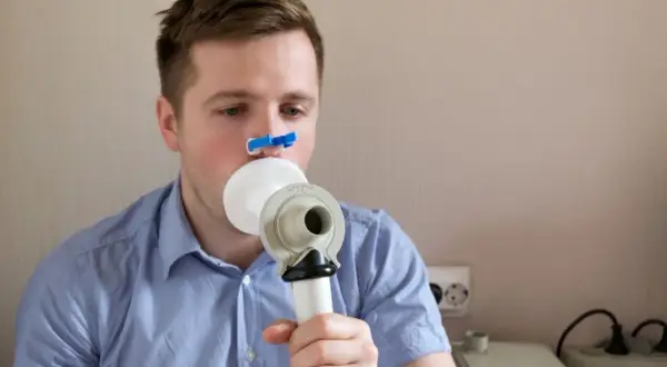Mężczyzna wykonuje spirometrię, badanie co wykrywa choroby płuc.