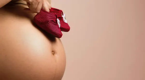 Dłoń trzyma malutkie czerwone buciki w kropki, symbolizujące przyszłe kroki maleństwa. To obrazek, który budzi myśl o rozwoju, o tym, jak szybko rośnie baby brain.