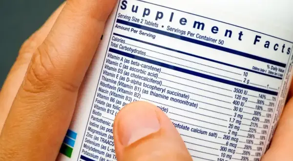 Palec wskazuje na etykietę "Supplement Facts", wyjaśniając, co to jest suplement diety i jakie składniki zawiera.