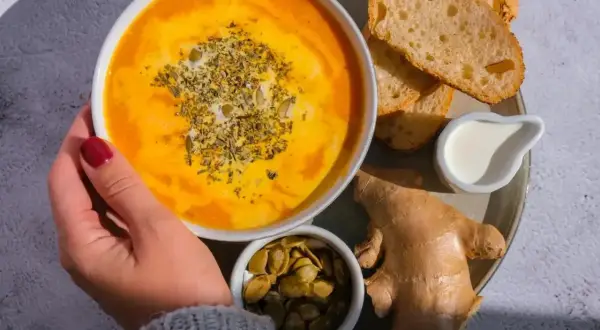 Rozgrzewająca zupa dyniowa z imbirem i pestkami dyni. Idealna, gdy zastanawiasz się, co jeść przy anginie. Podana z grzankami i śmietanką.