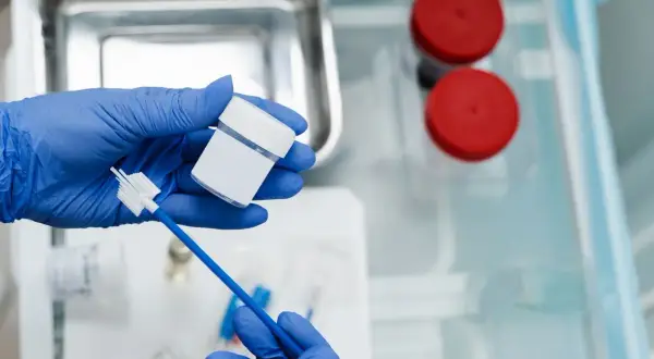 Rękawiczki medyczne trzymają pojemnik i szczoteczkę do pobierania wymazu. Przygotowanie do cytologii płynnej.