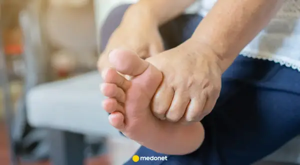 Dłoń masuje stopę, być może w poszukiwaniu ulgi. Badanie poziomu sodu i potasu może pomóc zrozumieć przyczynę dolegliwości.