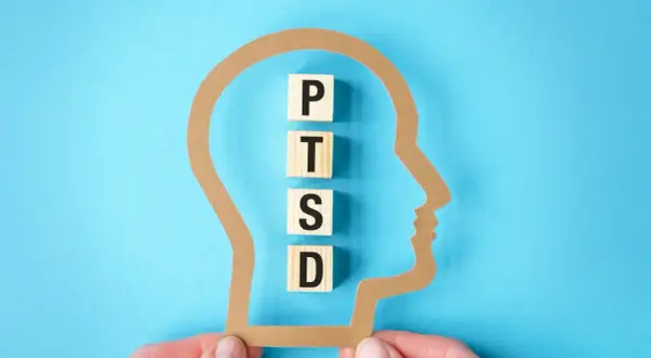 Klocki z literami P, T, S, D układają się w napis PTSD wewnątrz sylwetki głowy. Test na zespół stresu pourazowego.