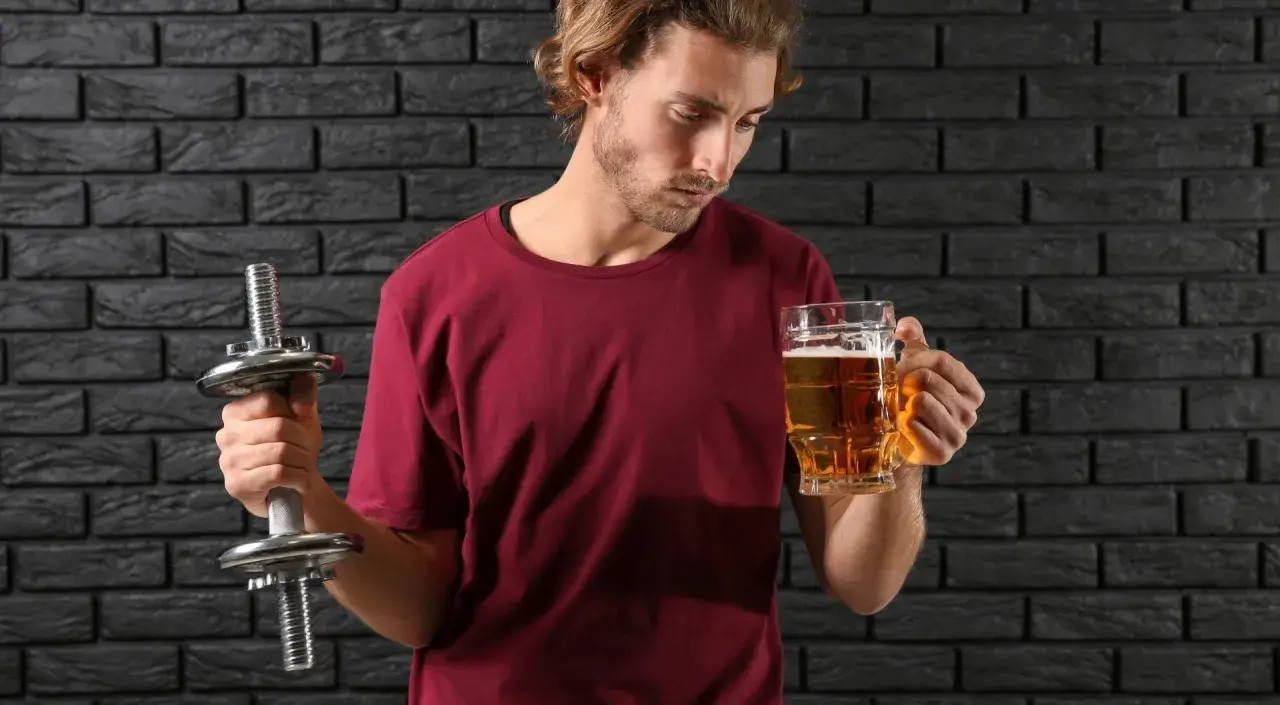Mężczyzna z hantlem zastanawia się, czy piwo bezalkoholowe ma alkohol.