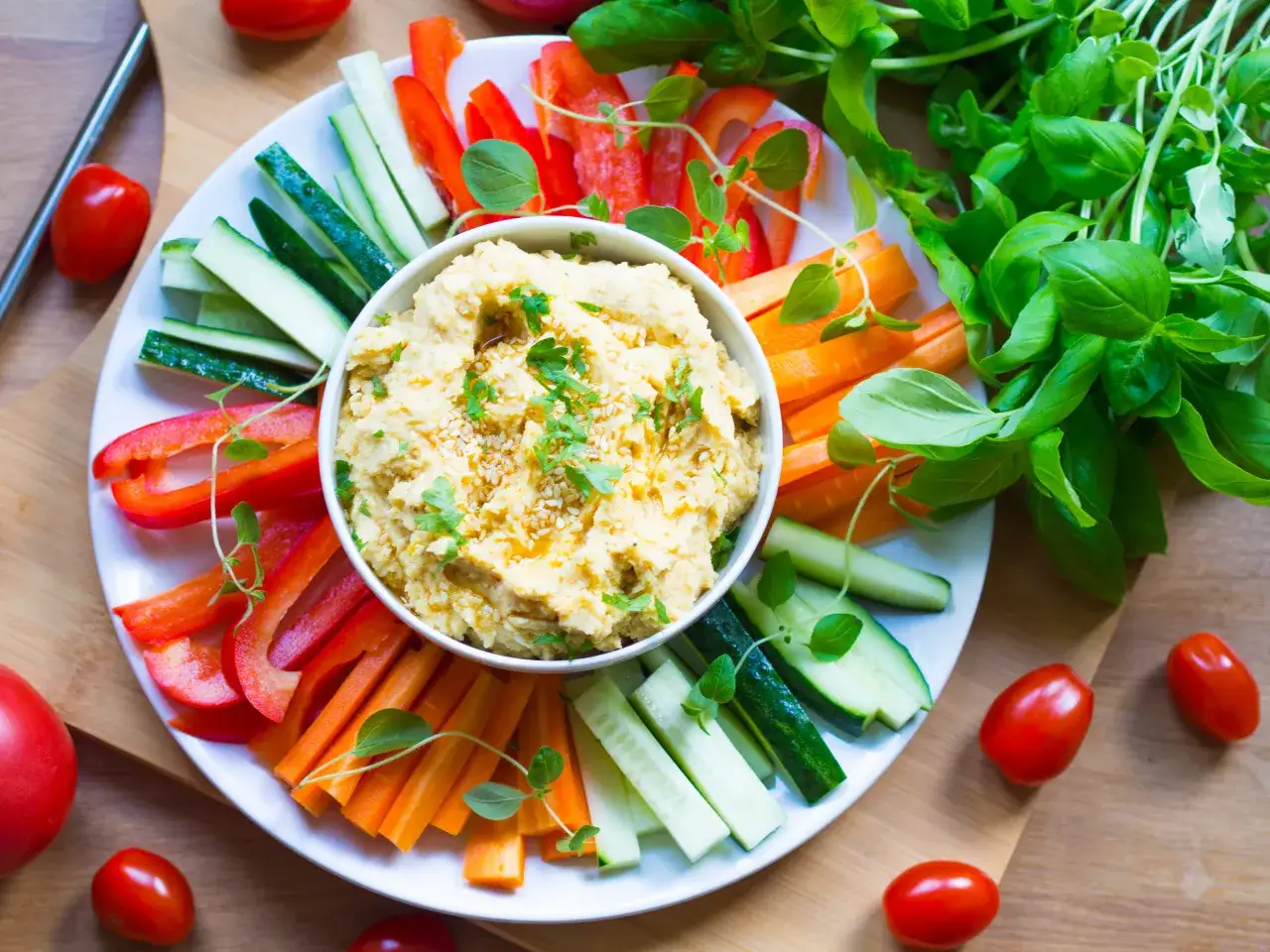 Pyszne, kremowe hummus z ciecierzycy, podane z kolorowymi warzywami: papryką, og&oacute;rkiem i marchewką. Idealna przekąska, kt&oacute;ra odpowie na pytanie: co to jest hummus?