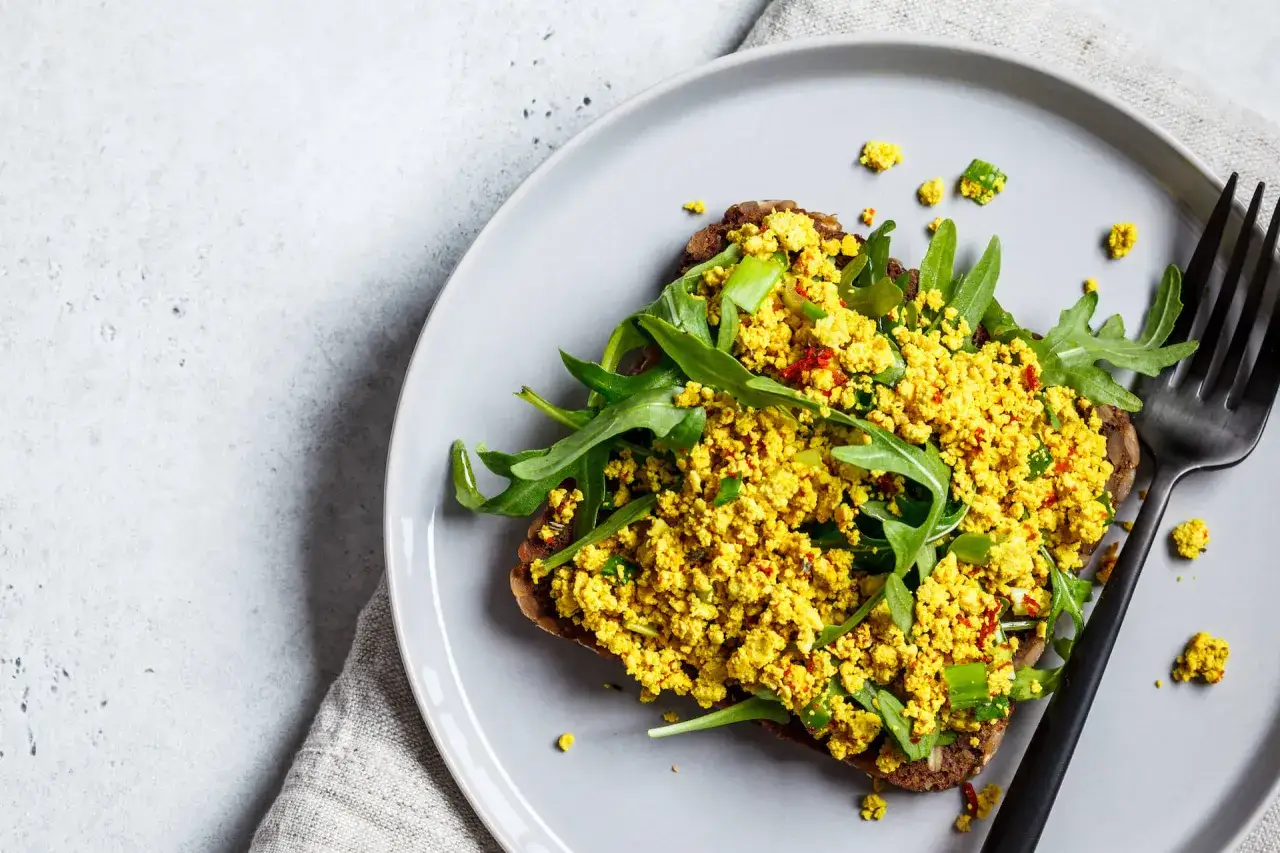 Tost z jajecznicą z tofu i rukolą, idealny na śniadanie w stylu dieta wysokobiałkowa.