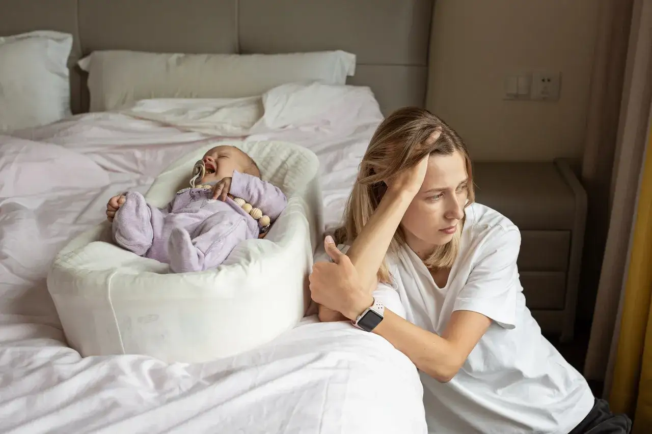 Zmęczona mama patrzy na płaczące dziecko. Czasem opieka nad maleństwem to prawdziwe wyzwanie dla baby brain.