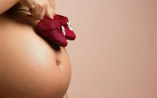 Dłoń trzyma malutkie czerwone buciki w kropki, symbolizujące przyszłe kroki maleństwa. To obrazek, który budzi myśl o rozwoju, o tym, jak szybko rośnie baby brain.